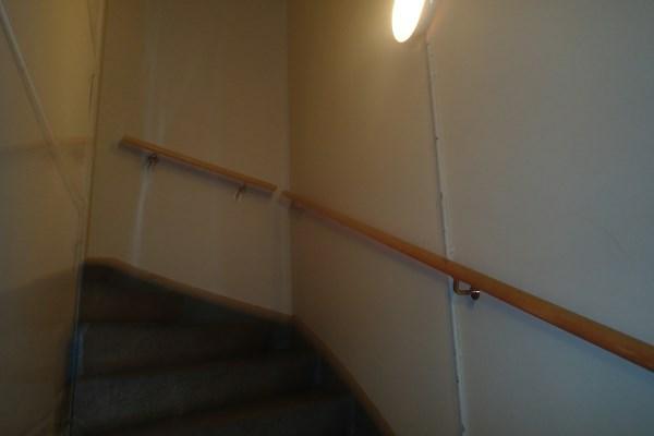 Det er ikke rekkverk da trapp er bygget rundt heishus. Det er stedvis ettermontert håndløper på vegg.